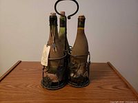 Front view of wrought iron holder containing four corked wine bottles
