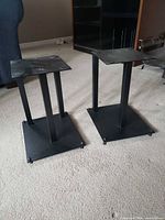 Two matching black metal speaker stands side by side showing overall design and condition