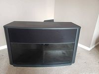 front view of black TV stand with speaker panel and glass doors closed