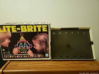 Box front with Lite-Brite branding, children assembling clown design, unit beside box