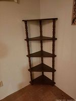 Full view of five-tier wooden corner shelf standing in corner