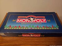 Closed blue box top showing Monopoly Deluxe Anniversary Edition graphics