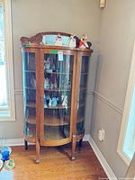 Full front view of curved glass cabinet showing door, shelves, legs
