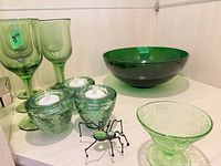 Group shot of all green glass items, tealight holders with LED candles, metal spider