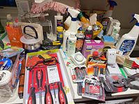Overall view showing screwdrivers, staple tool, batteries, cleaners and household items piled on tabletop