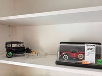 Shelf view showing all three model cars: Ford Model T, crystal car, Stutz in case