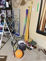 Group view of assorted sports equipment leaning against wall and on floor