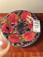 Top view of Moorcroft plate showing fruit/floral design and rim chips