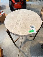 Full view of round travertine side table on metal base