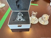 Baby figurine in open presentation box beside bear and owl figurines