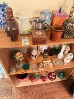 Wood shelving unit showing assorted ceramic, glass, wood and metal decorative pieces