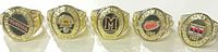 All five replica championship rings lined up showing face designs and years