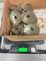 Box containing multiple coils of galvanized nails on scale