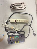 All three items: grey Belkin power strip, beige power strip, coiled ivory extension cord