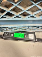 Digital scale displaying 51.4 lb under container holding nails