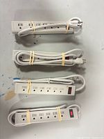 Four gray power strips bundled with cords visible