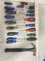 Full layout of 18 screwdrivers and claw hammer beside rulers