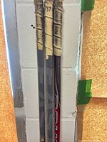 Three composite hockey sticks leaning against wall, taped handles visible
