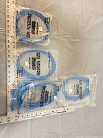 Four sealed blue Cat5e patch cables in packaging next to rulers for scale