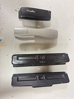 Overview of two staplers and two hole punches aligned on tabletop