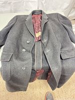 Full view of gray overcoat laid flat showing three-button front and lapel