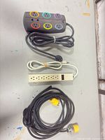 All three items laid out: gray power strip, ivory power strip, heavy-duty twist-lock cord