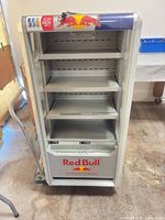Front view showing open display area, four shelves, Red Bull branding, ventilation grille
