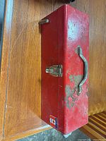 Top view of closed red toolbox showing handle, latch and wear