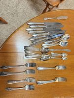 Full lot overview on table showing assortment of knives, forks and spoons