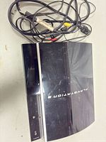 Top view of black PS3 console with attached cables