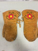 Pair of mittens fronts showing embroidery and ties