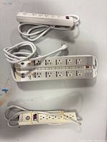 All three power strips laid out: Belkin PureAV 12-outlet unit, white 5-outlet strip, beige 6-outlet strip