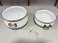 both enamel pieces side by side displaying size difference and brass handles