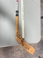 Natural wood stick with signatures on blade and white shaft portion beside second stick