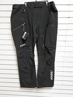 Front view of FXR black Tri-Lam pant hanging, tags attached