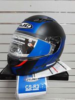 Left front view of HJC CS-R3 blue/black helmet with tags and manual visible