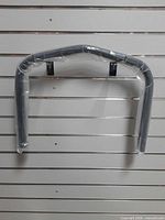 Black tubular rear bumper wrapped in plastic with mounting brackets