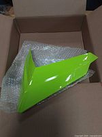 Top view of neon green windshield retainer in box with bubble wrap