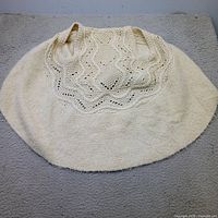 Full view of cream open knit vest laid flat showing crochet pattern and overall shape