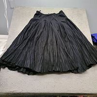 Full view of black pleated skirt laid flat