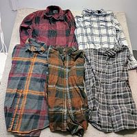 All five flannel shirts laid flat showing fronts and patterns