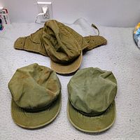 All three caps laid out: cold-weather cap on top, two utility caps below