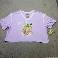 Front view of lavender Nickelodeon crop t-shirt with graphic and tag