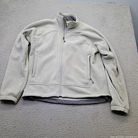 Front view of light grey fleece jacket showing full-zip design and hand pockets
