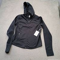 Front view of black zip hoodie with hood and tag attached