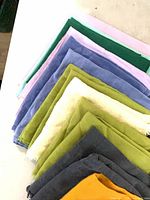 Stack of multi-colored cloth napkins showing variety of colors and edge conditions
