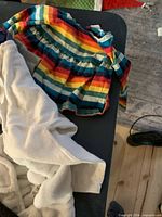 Group of baby clothes including rainbow dress and white fleece onesie