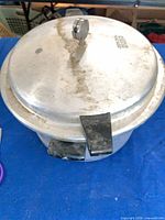 Closed pressure cooker showing lid, vent weight, and handles