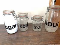 Front view of four labeled glass clamp-top jars