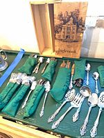 Entire flatware set laid out in green sleeves with serving pieces and Inglenook box